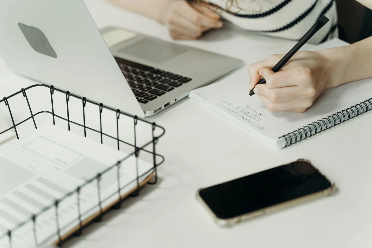 Handschriftliche Notizen neben Laptop und Smartphone