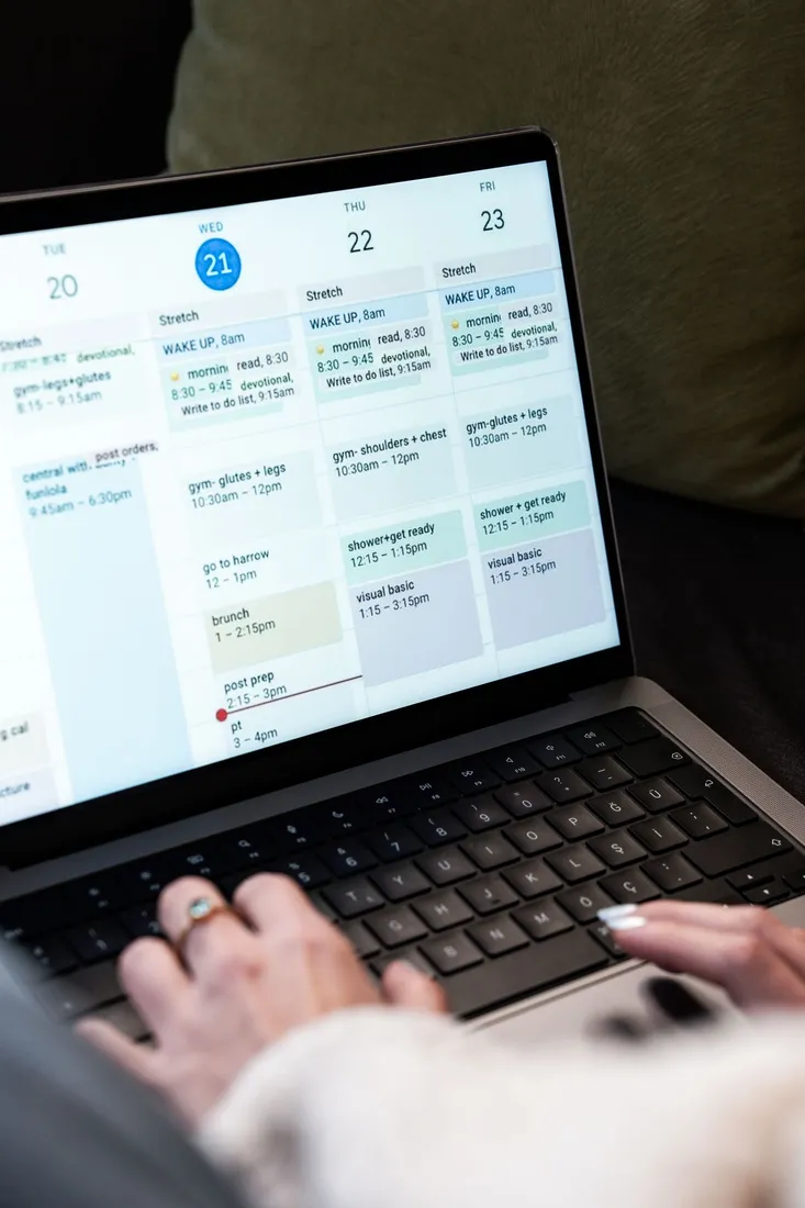 Hände an einem Laptop mit einem geöffneten digitalen Kalender