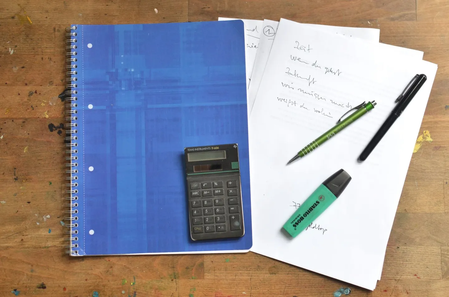 Taschenrechner, Notizbuch und Stifte auf einem Schreibtisch