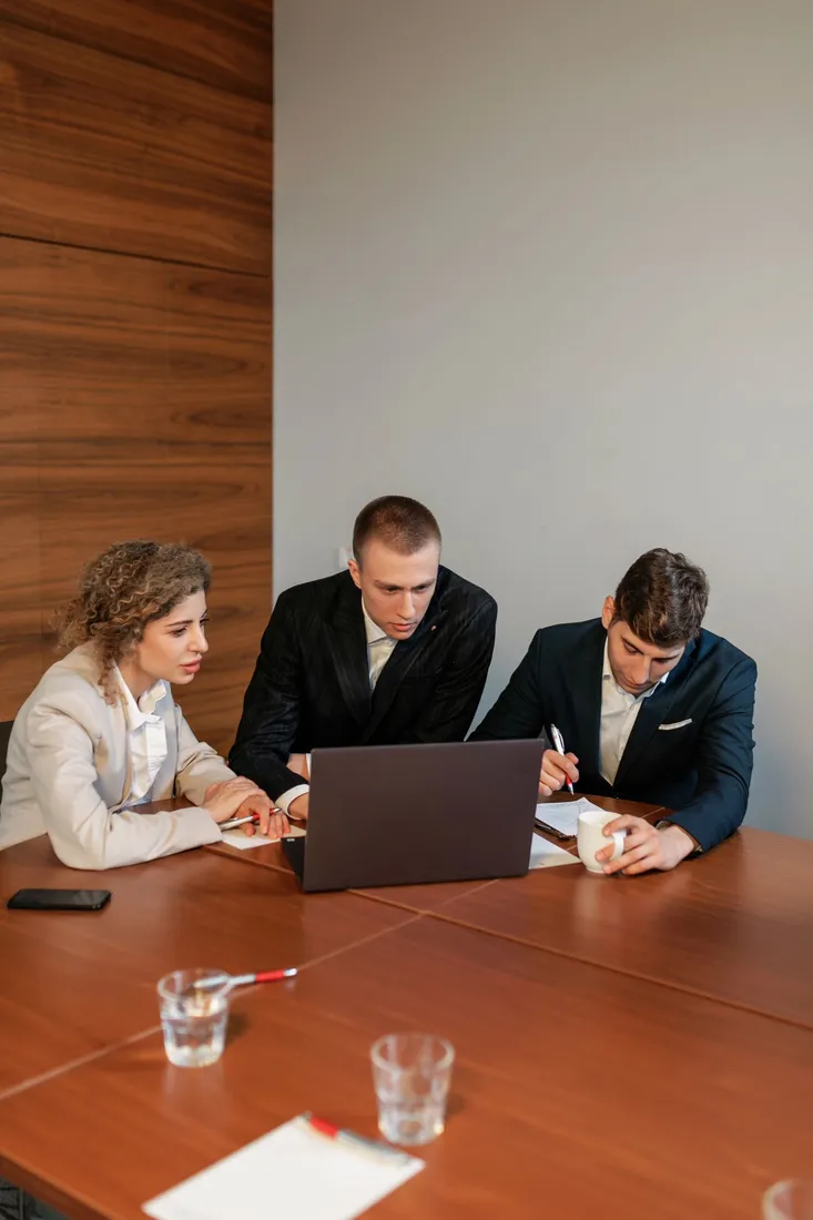 Drei Personen besprechen gemeinsam Inhalte an einem Laptop
