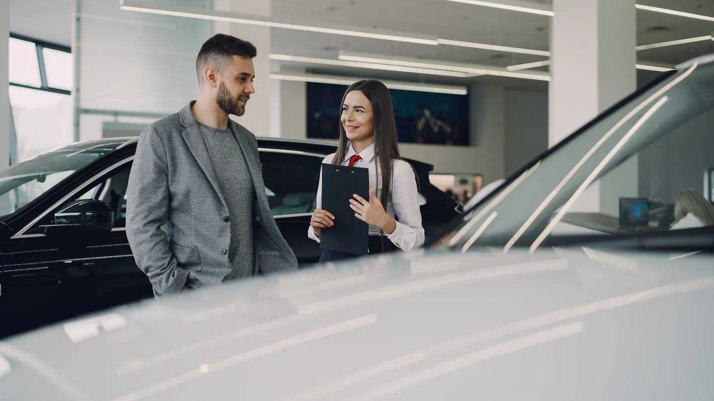 Zwei Personen im Gespräch neben einem Auto im Verkaufsraum