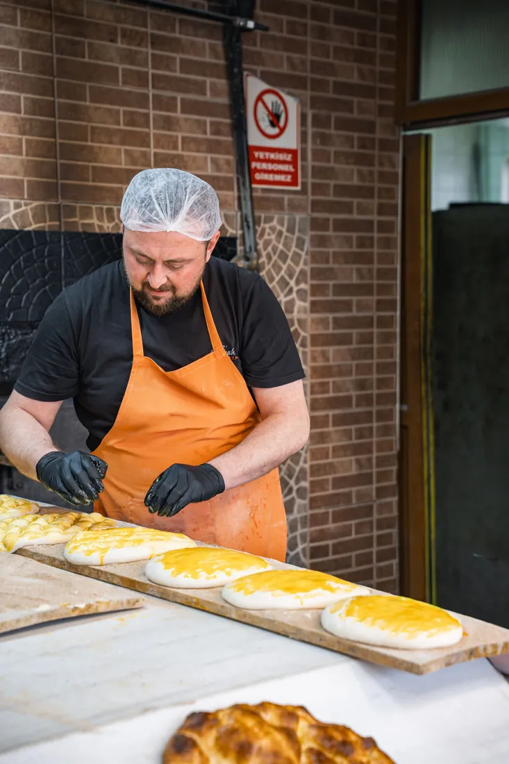 Bäcker mit orangefarbener Schürze bereitet Brot vor