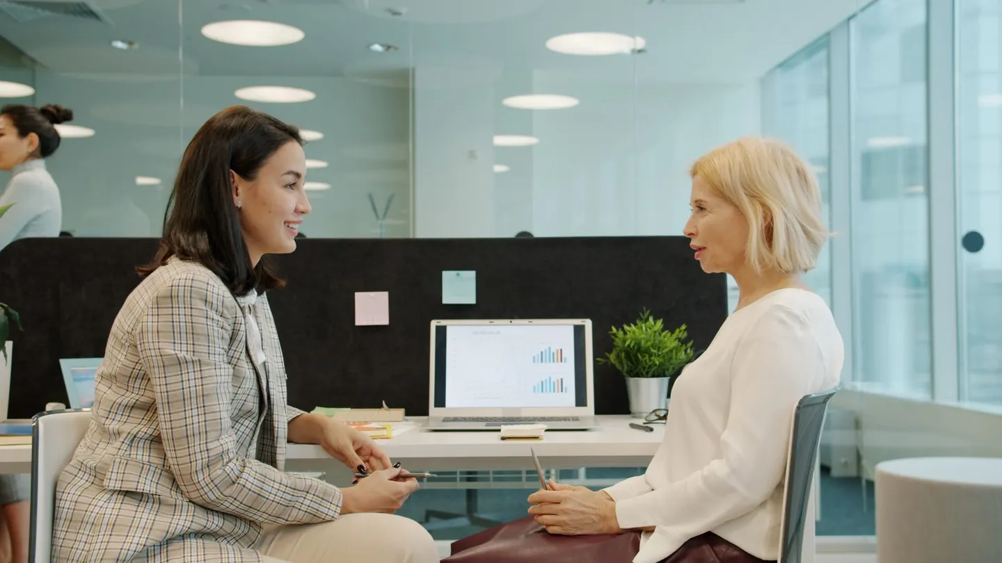Zwei Frauen im Gespräch an einem Tisch im Büro