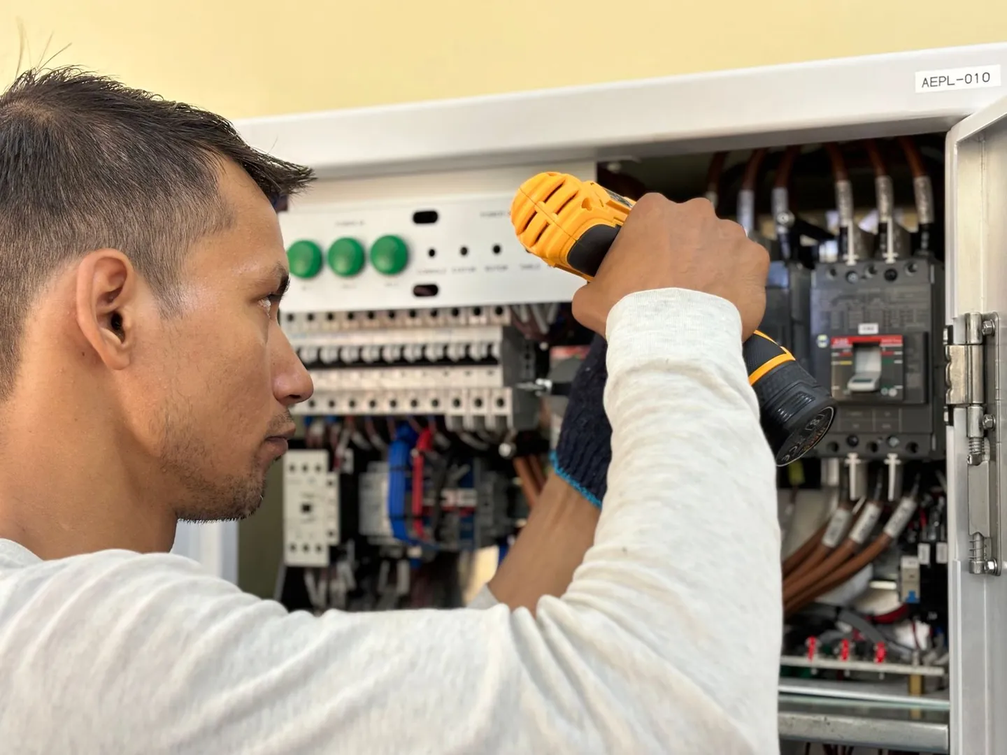Person arbeitet an einem geöffneten elektrischen Schaltschrank