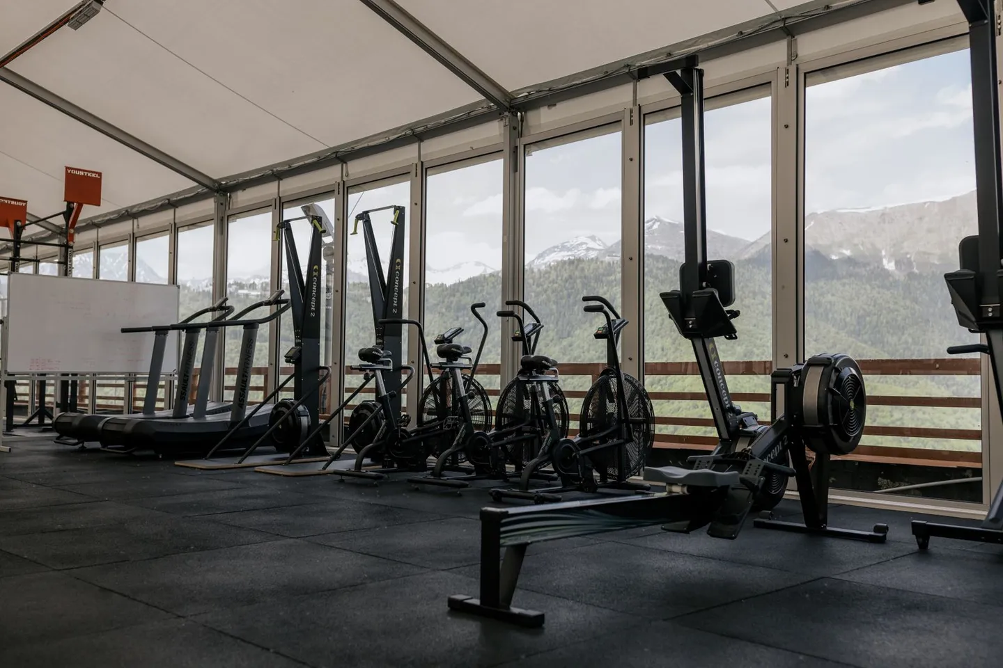 Trainingsgeräte vor großen Fenstern mit Blick auf die Berge