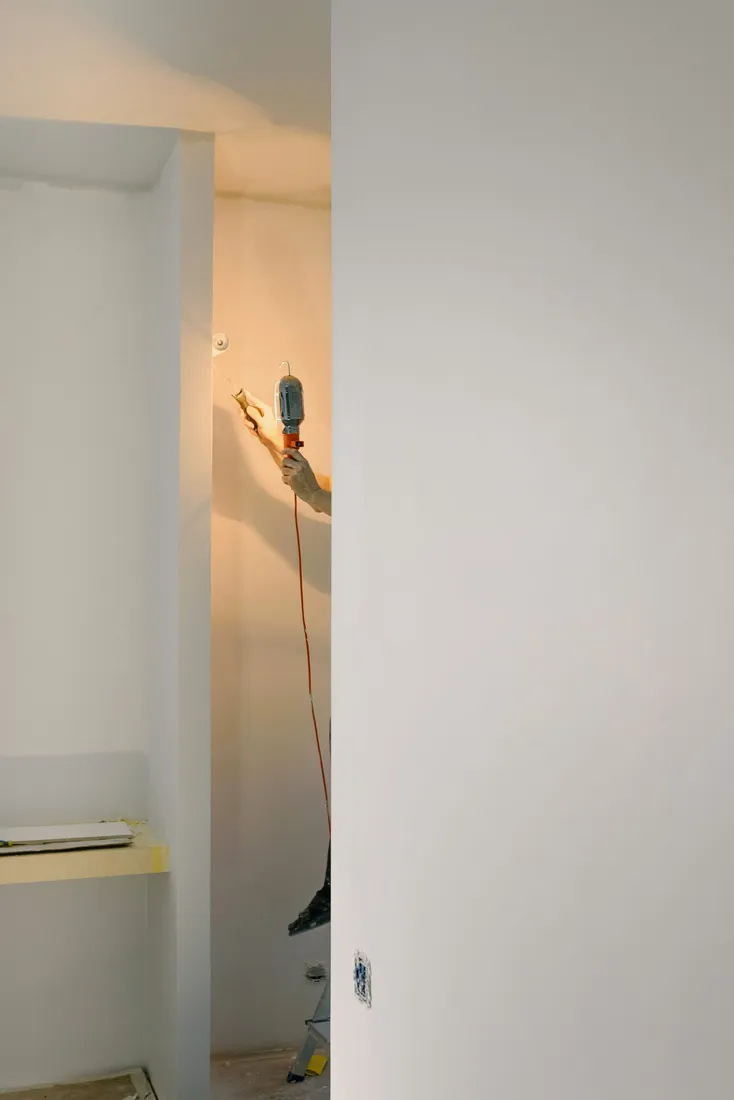 Person auf einer Leiter arbeitet an einer Leuchte