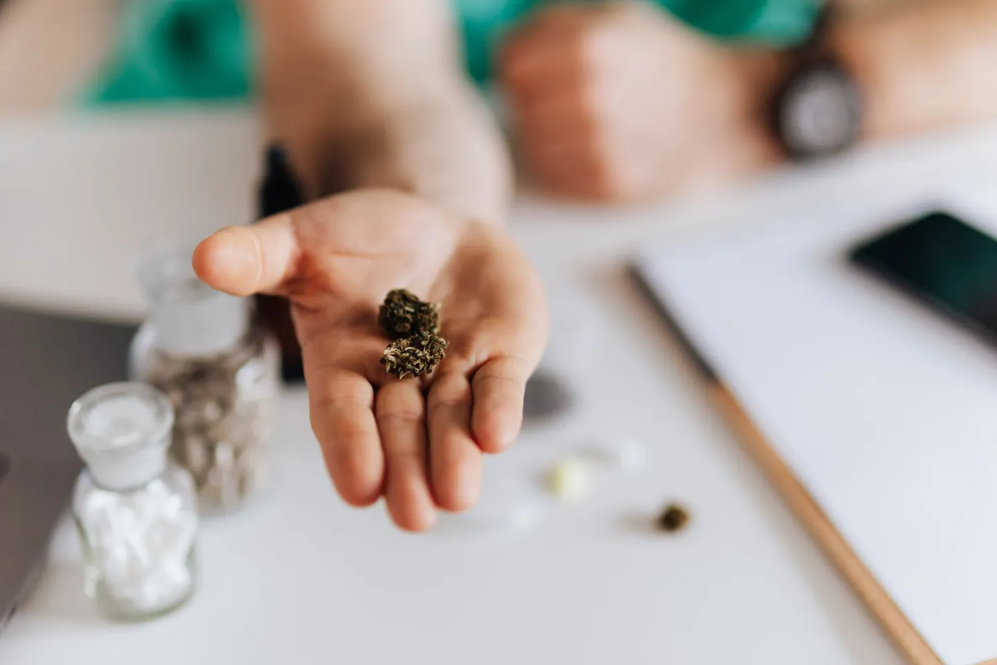 Hand mit getrocknetem Pflanzenmaterial über einem Tisch