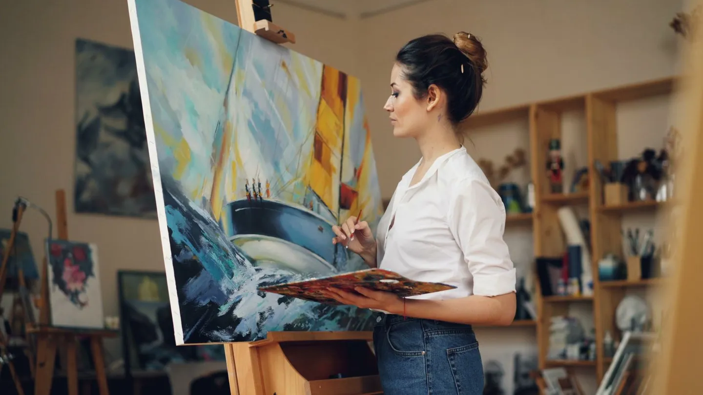 Künstlerin mit Farbpalette vor einer Leinwand im Atelier