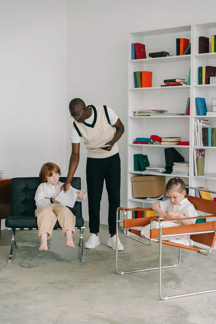 Erwachsener arbeitet mit Kindern an einem Tisch