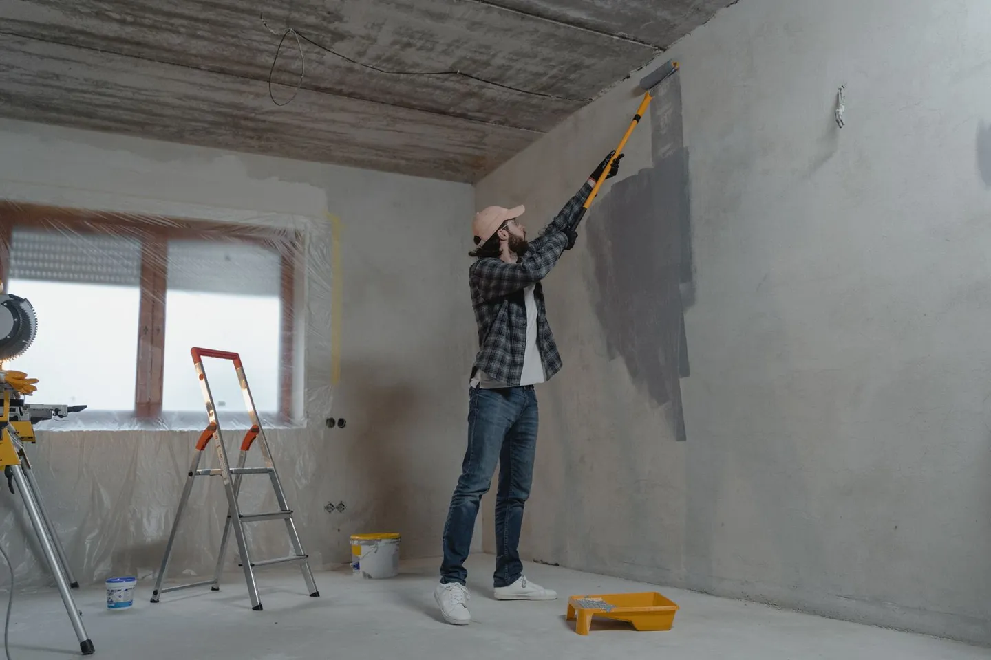 Mann streicht eine Innenwand mit einer Farbrolle