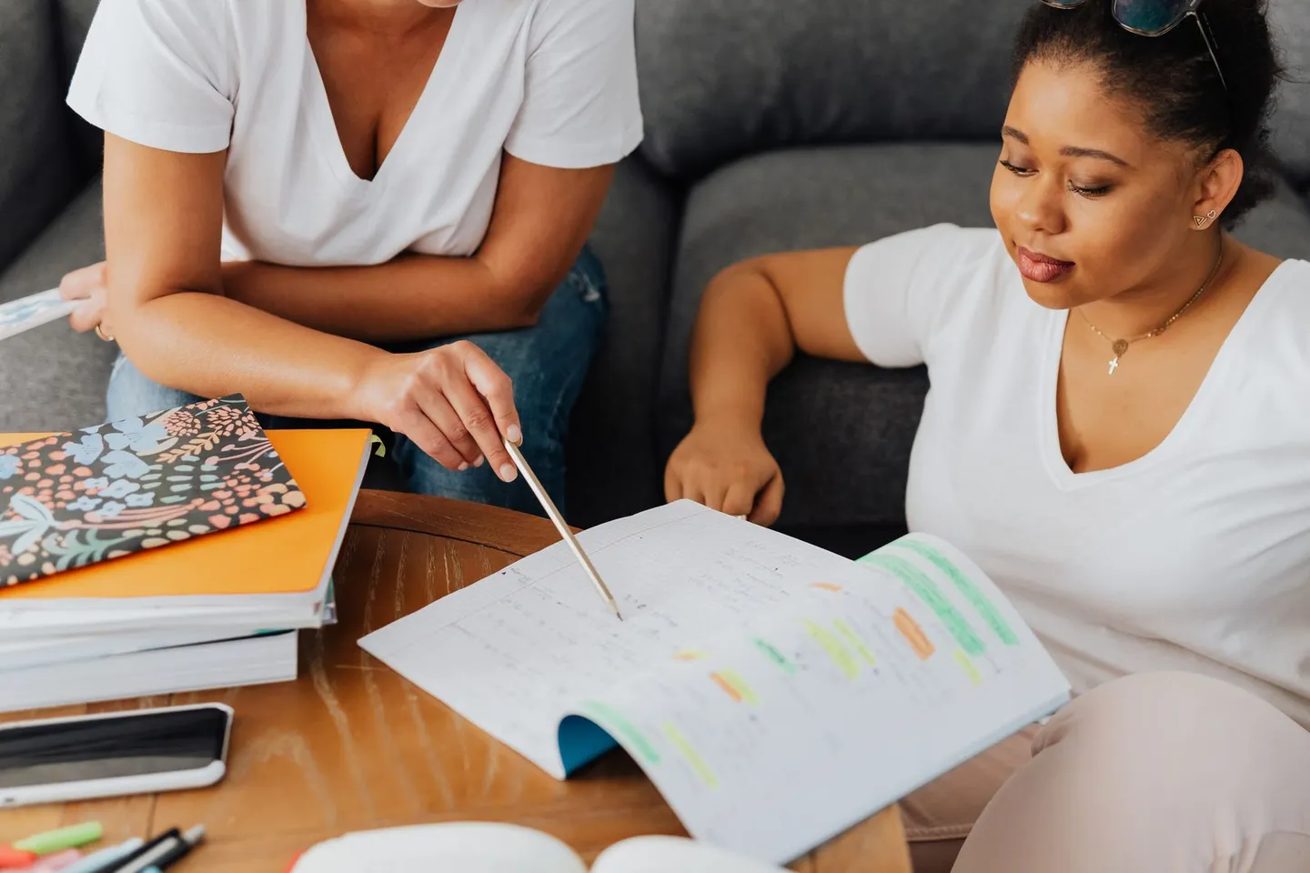 Zwei Personen arbeiten gemeinsam mit einem aufgeschlagenen Heft