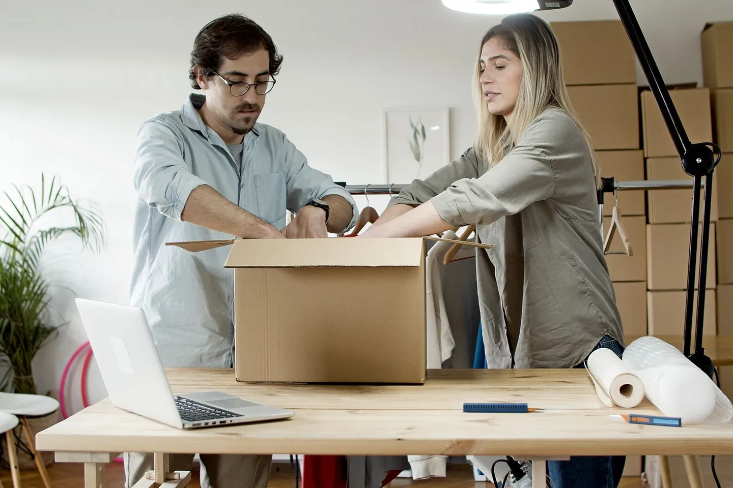 Zwei Personen verpacken Waren in einem Versandkarton