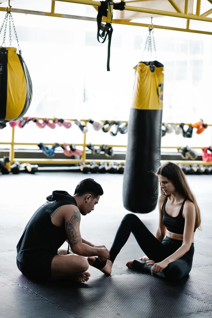 Zwei Personen beim Anlegen von Handbandagen im Trainingsraum