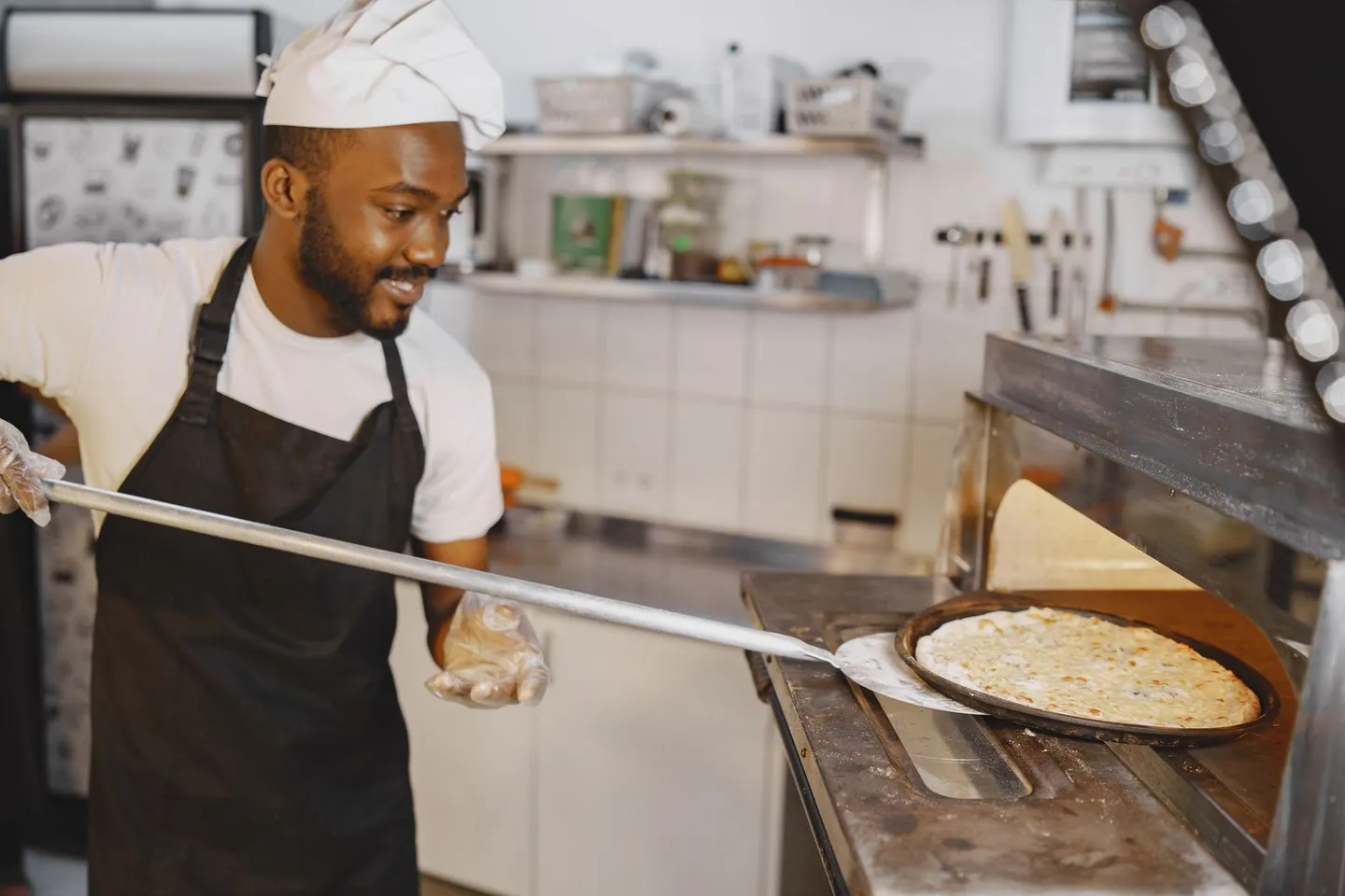 Koch zieht eine Pizza mit einer Schaufel aus dem Ofen
