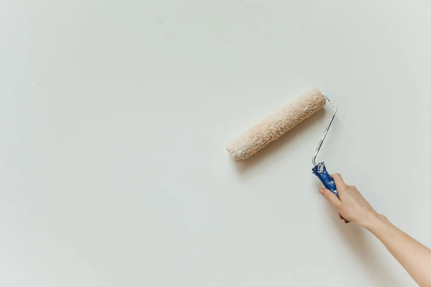 Hand mit Farbrolle beim Streichen einer Wand