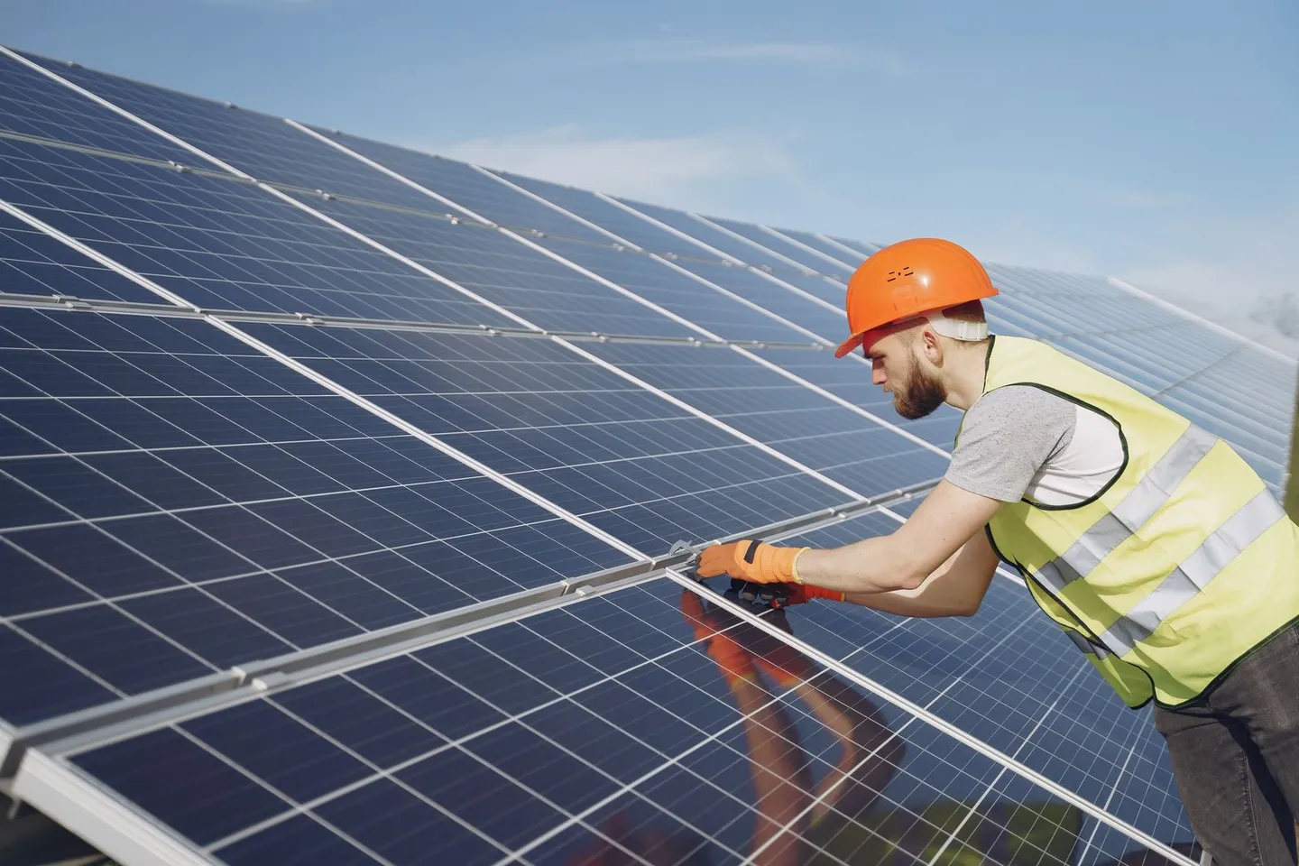 Person mit Schutzhelm prüft Solarmodule