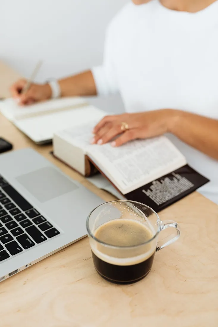 Handschriftliche Notizen neben einem Laptop und einer Tasse