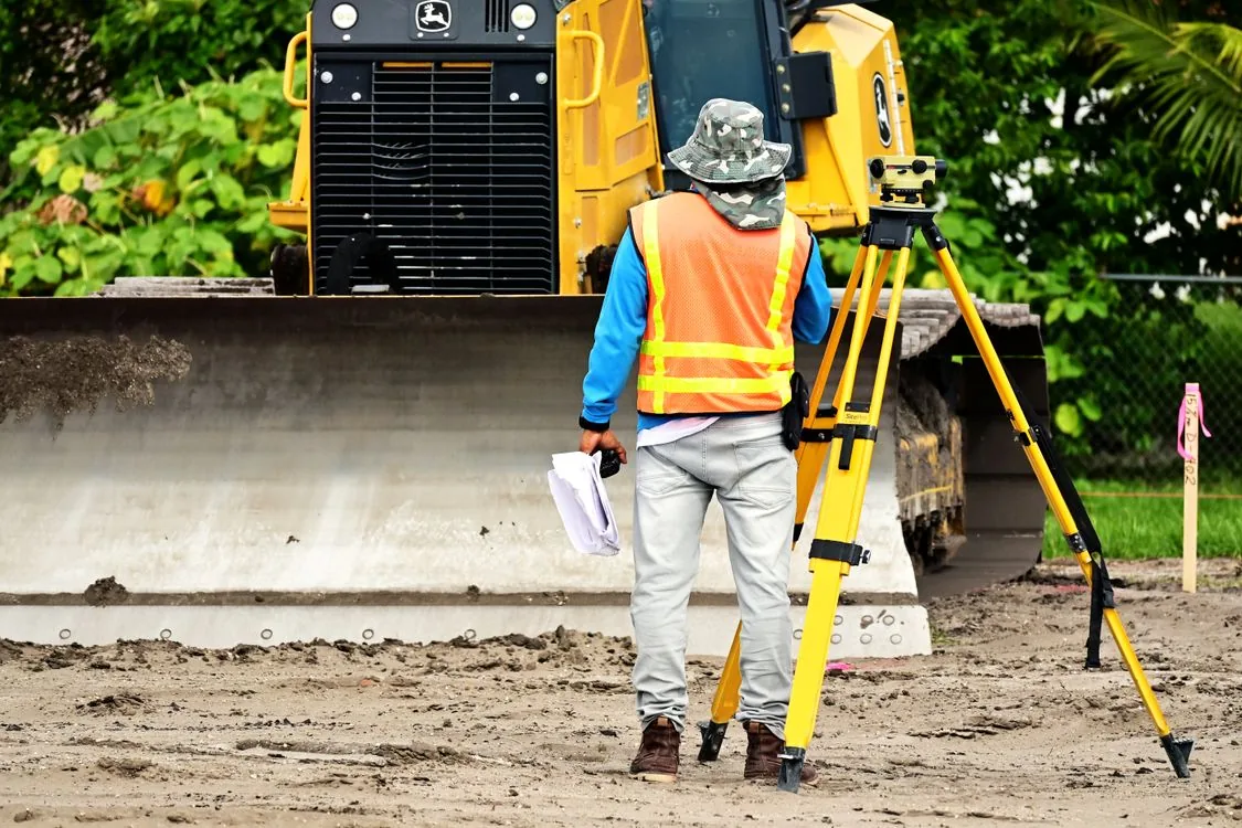 Vermesser mit Messgerät an einer Baustelle